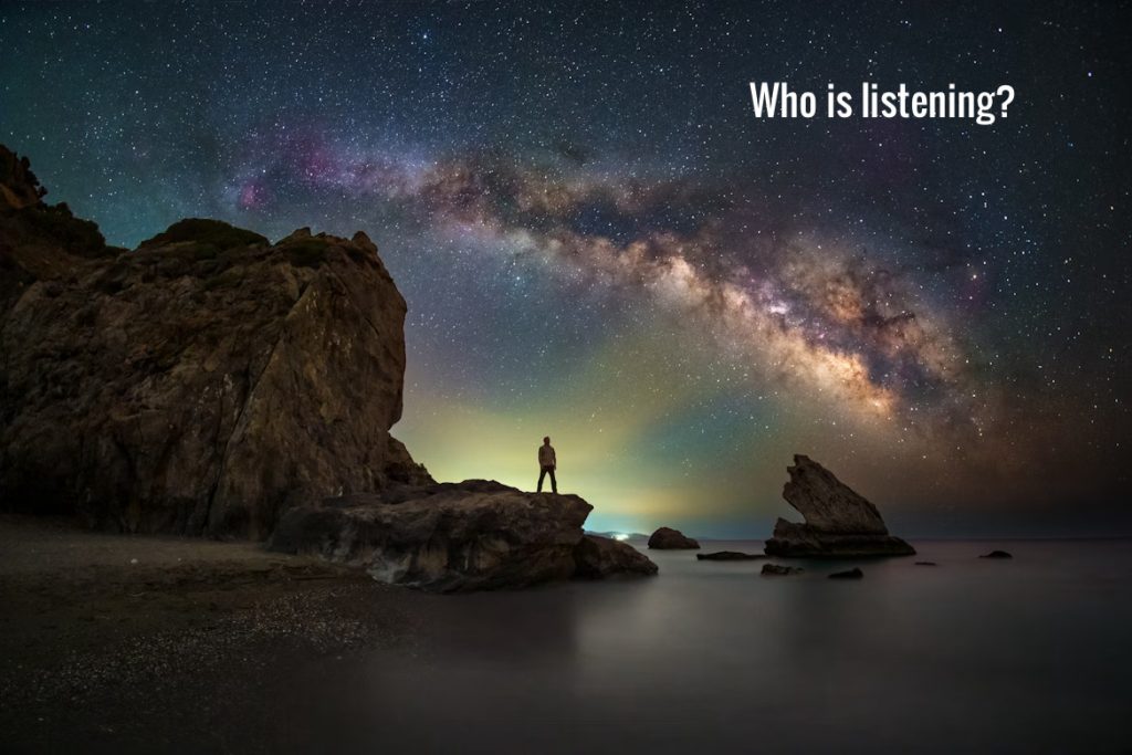 Person stargazing under Milky Way on rocky shore.