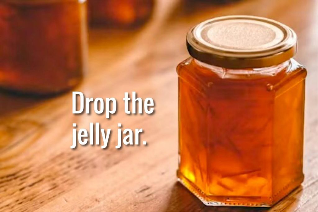 Hexagonal orange jelly jar on wooden table.