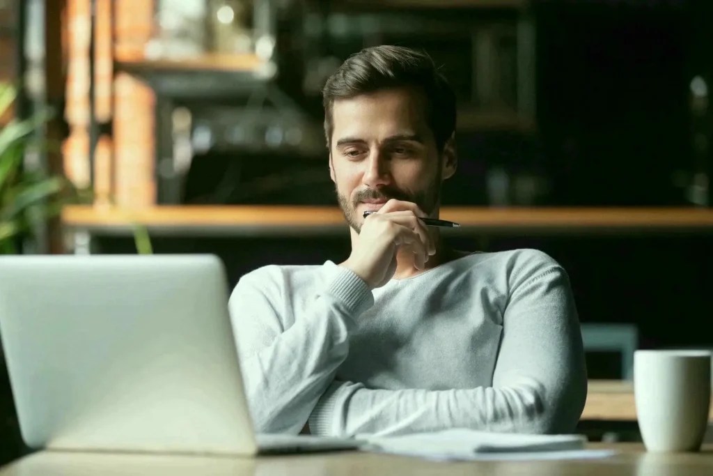 Person thoughtfully looking at laptop in office