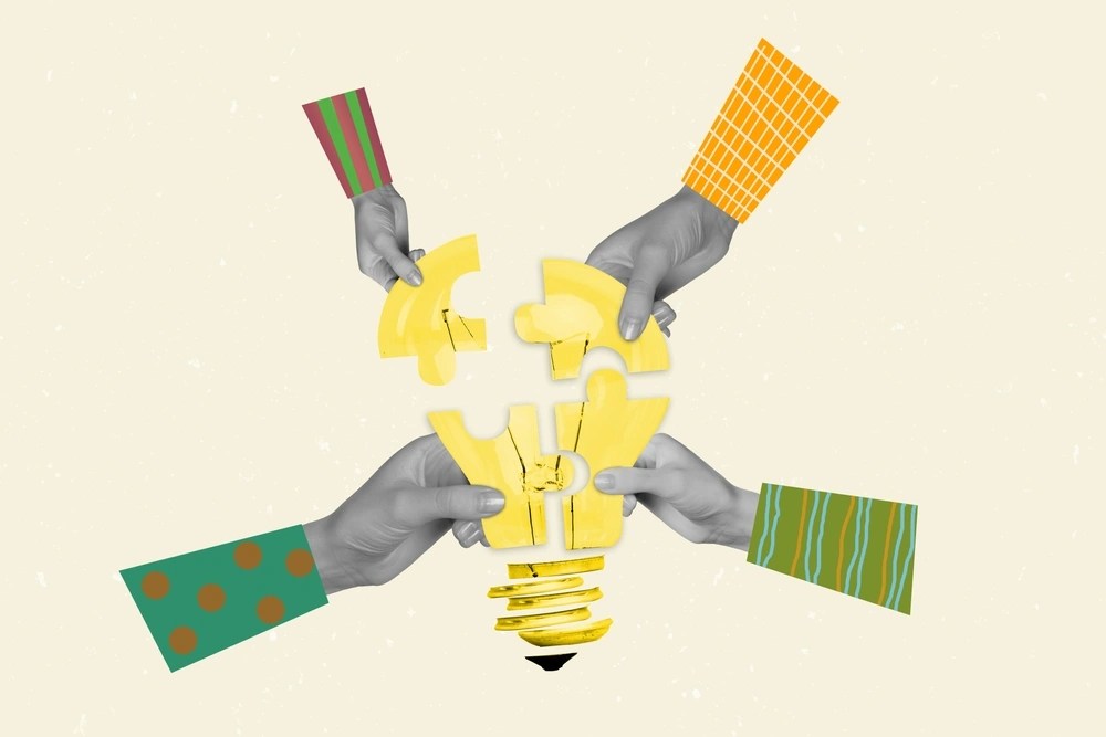Hands assembling puzzle pieces into lightbulb shape