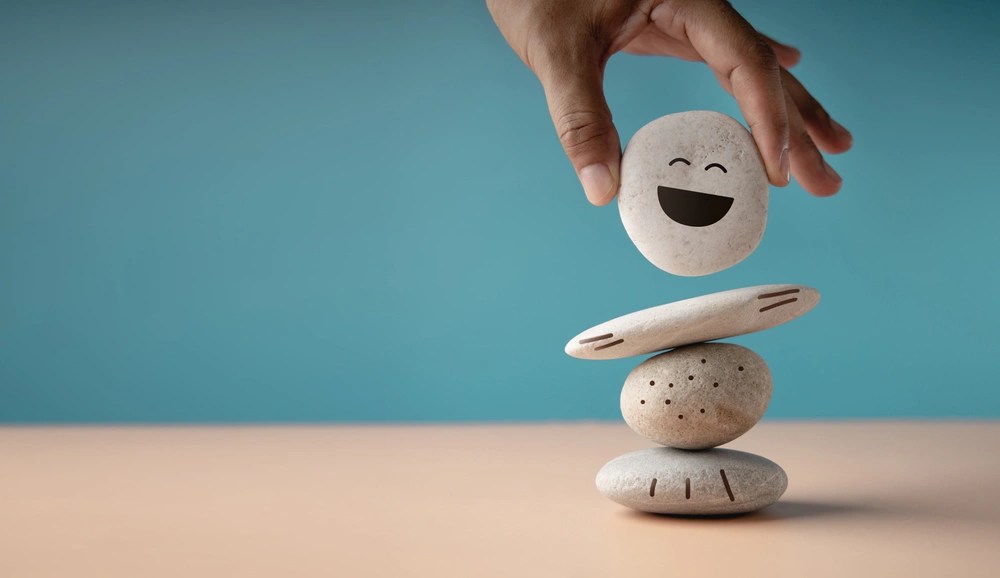 Hand stacking smiling rocks on surface