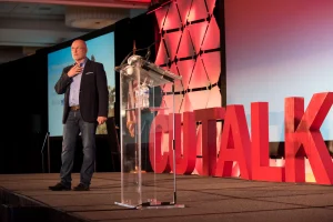 Speaker presenting on stage at conference event.
