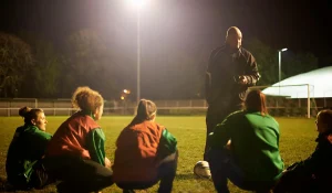 Soccer coach instructs team during nighttime practice.