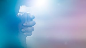 Hands clasped in prayer with soft focus.