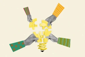 Hands assembling puzzle pieces into lightbulb shape