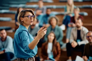 Woman speaking to audience in lecture setting.